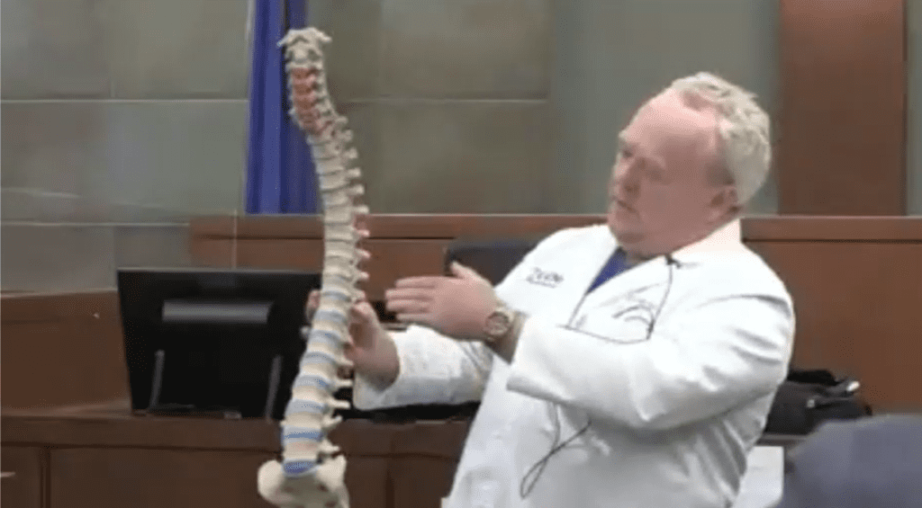 Image of doctor holding a 3D printed spine in a courtroom